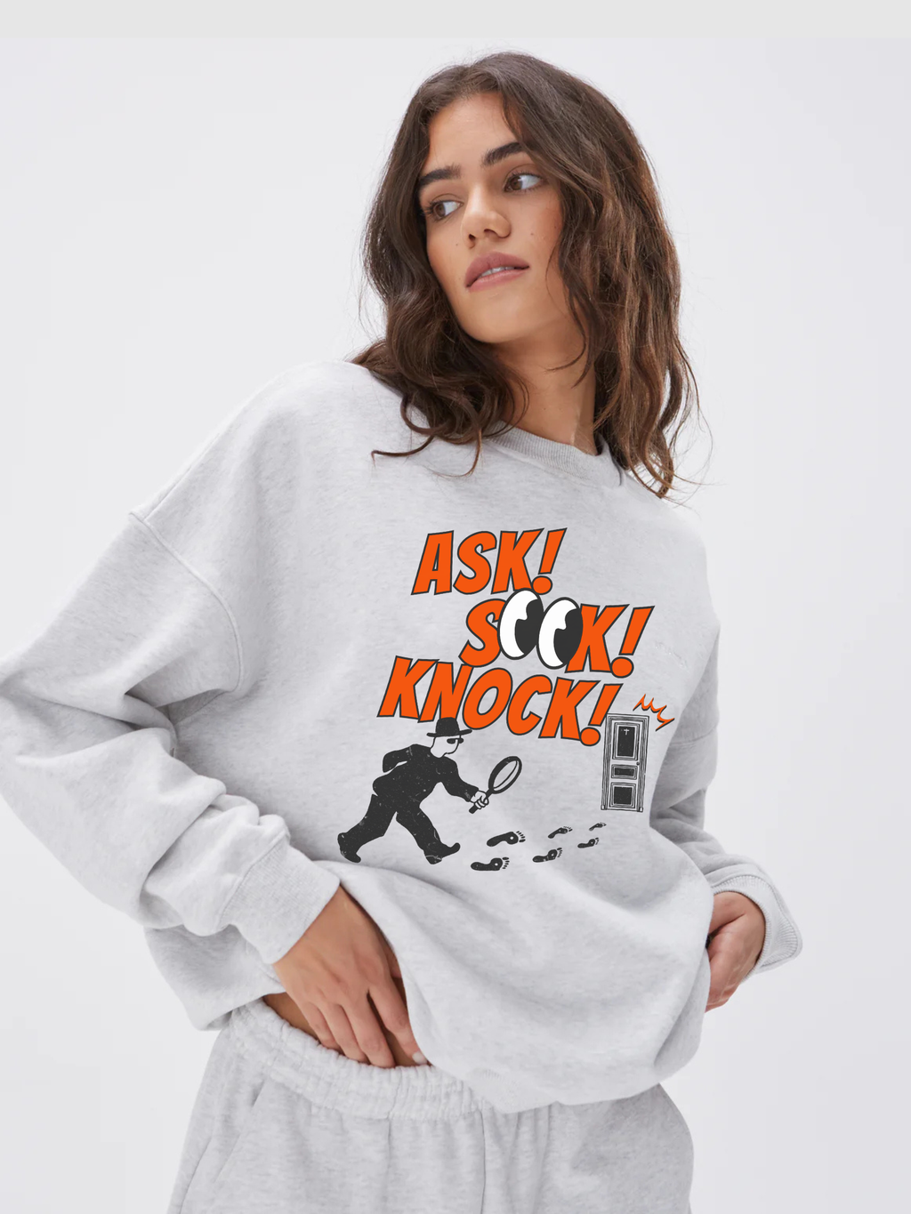 Woman wearing the SĒK Apparel Ask, Seek, Knock Crewneck in heather gray — front view of Christian crewneck sweatshirt with 'Ask Seek Knock' graphic, on white background