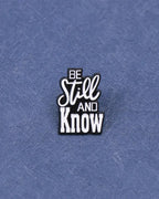 SĒK Apparel Be Still and Know enamel pin — faith-inspired Christian lapel pin with 'Be Still and Know' text referencing Psalm 46:10, front view 