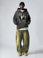 Man wearing the SĒK Apparel Be the Light Hoodie in dark gray with green pants and beanie — scripture-inspired streetwear hoodie