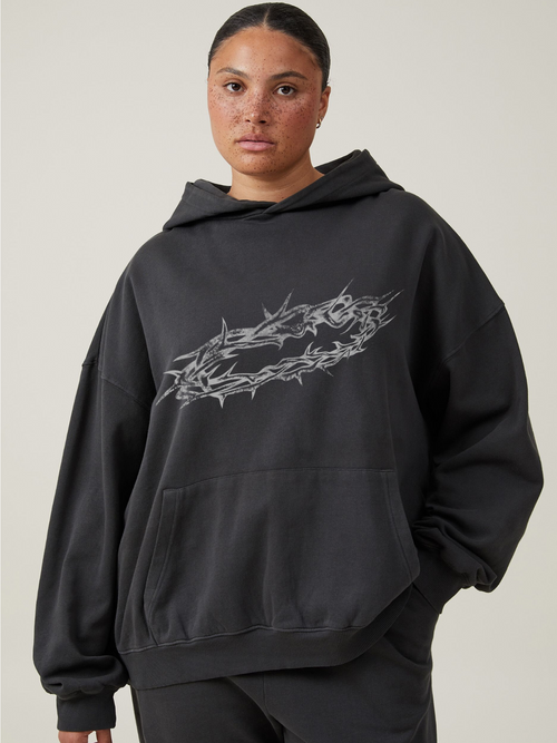Woman wearing the SĒK Apparel By His Wounds Hoodie in washed black — front view with crown of thorns graphic, faith-inspired Christian hoodie referencing Isaiah 53:5