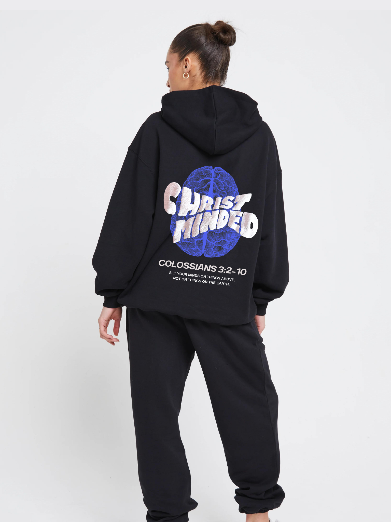 Woman wearing the SĒK Apparel Christ-Minded Hoodie in black — back view with 'Christ-Minded' text and Colossians 3:2-4 scripture print, faith-inspired Christian hoodie