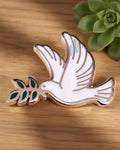 A brooch pin shaped like a silver dove with olive branch in its mouth