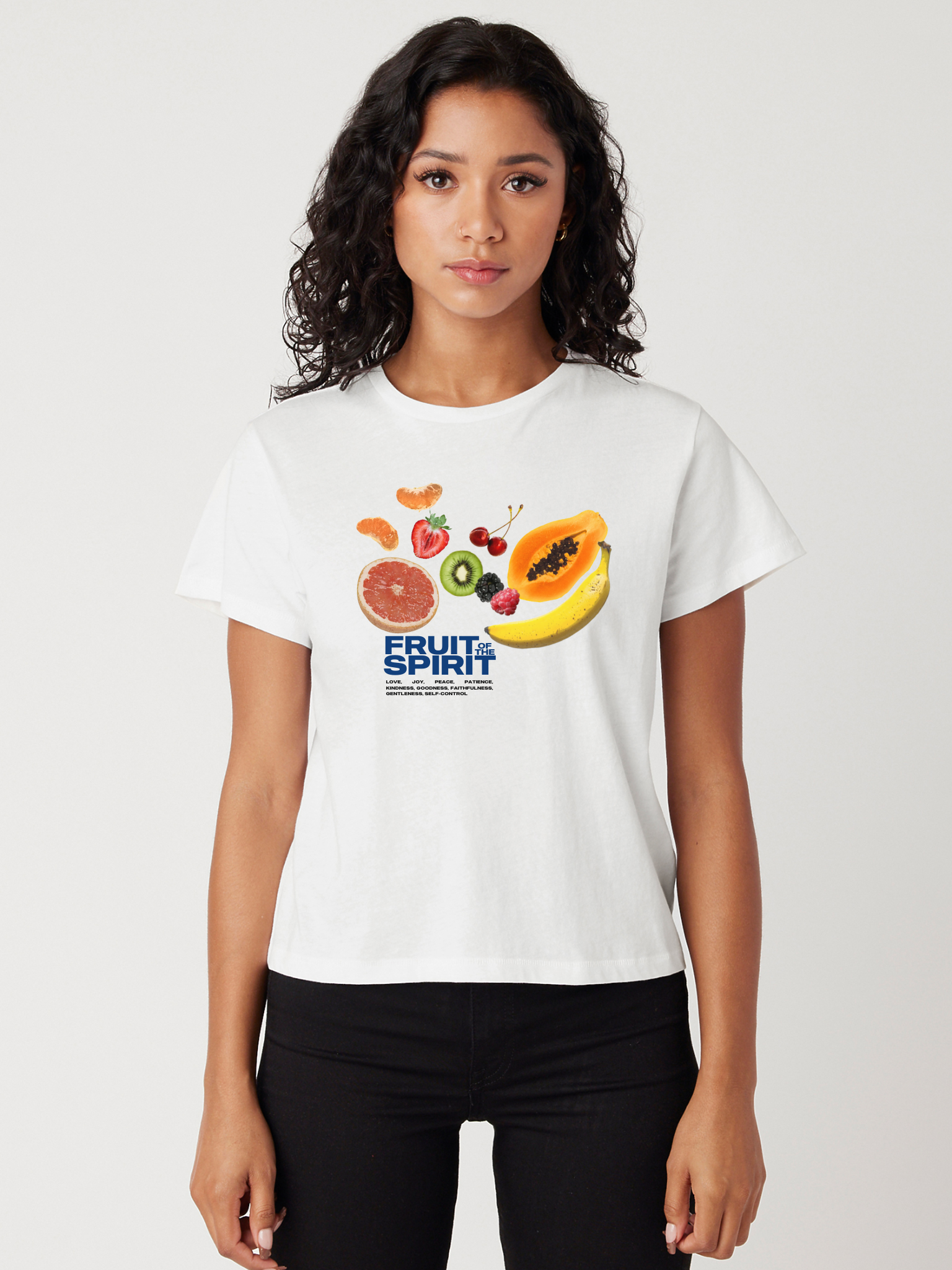 A woman wearing a white cropped t-shirt with a printed design featuring an assortment of fruits and the text 'Fruit of the Spirit'.