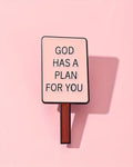 Sign with 'GOD HAS A PLAN FOR YOU' text on a pink background