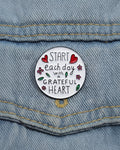 SĒK Apparel Grateful Heart enamel pin — round floral Christian lapel pin with 'Grateful Heart' text and heart details, faith-inspired accessory