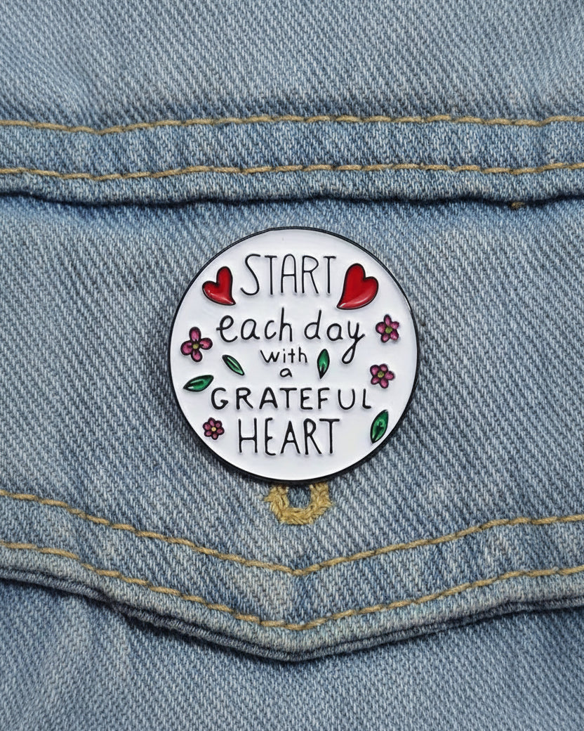 SĒK Apparel Grateful Heart enamel pin — round floral Christian lapel pin with 'Grateful Heart' text and heart details, faith-inspired accessory