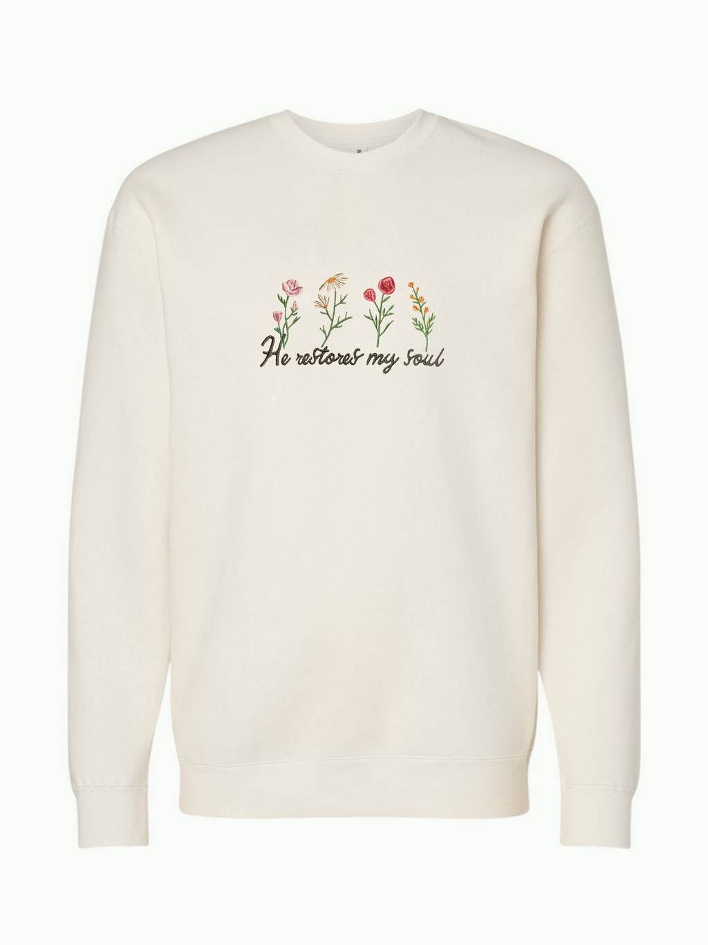 SĒK Apparel He Restores Crewneck in beige — flat lay of faith-inspired Christian sweatshirt with embroidered 'He Restores' text and floral detail, referencing Psalm 23:3