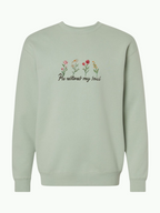 SĒK Apparel He Restores Crewneck in sage — flat lay of faith-inspired Christian sweatshirt with embroidered 'He Restores' text and floral detail, referencing Psalm 23:3