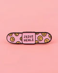 Pink bandaid with smiley faces and 'Jesus Heals' text on a pink background