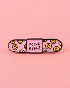 Pink bandaid with smiley faces and 'Jesus Heals' text on a pink background