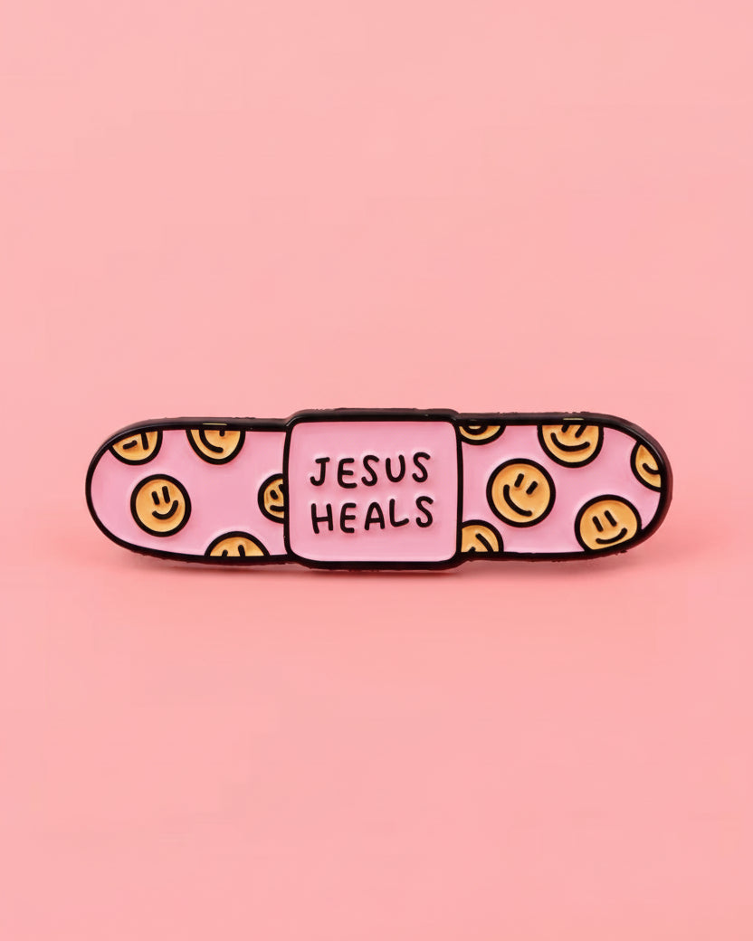 Pink bandaid with smiley faces and 'Jesus Heals' text on a pink background