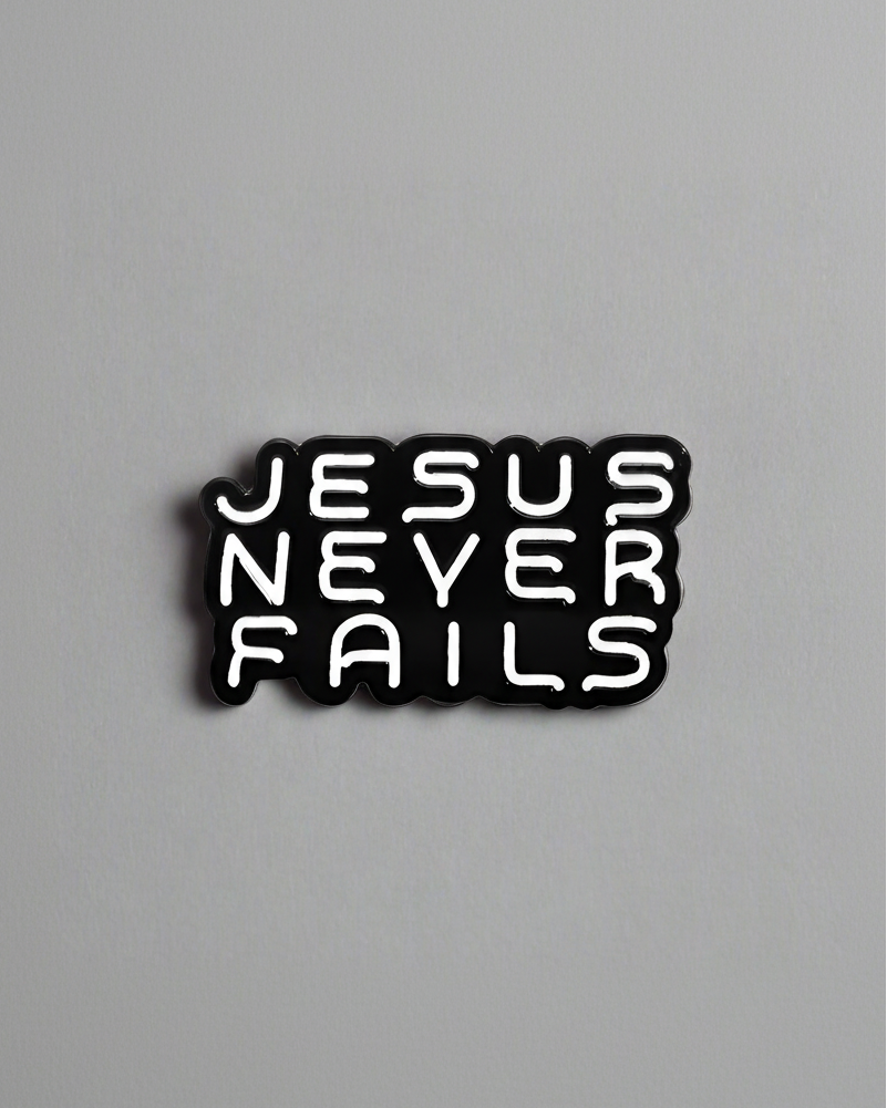 SĒK Apparel Jesus Never Fails enamel pin — black pin with 'JESUS NEVER FAILS' in bold white letters, faith-inspired Christian lapel pin