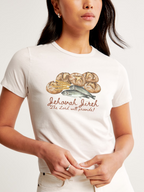 Woman wearing the SĒK Apparel Jehovah Jireh Baby Tee in off-white — faith-inspired Christian graphic tee with bread illustration and 'Jehovah Jireh — The Lord Will Provide' text, referencing Genesis 22:14 and Matthew 14:16