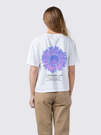 Woman wearing the SĒK Apparel Made New Flower Tee in white — back view with floral design and 2 Corinthians 5:17 scripture, faith-inspired Christian graphic tee