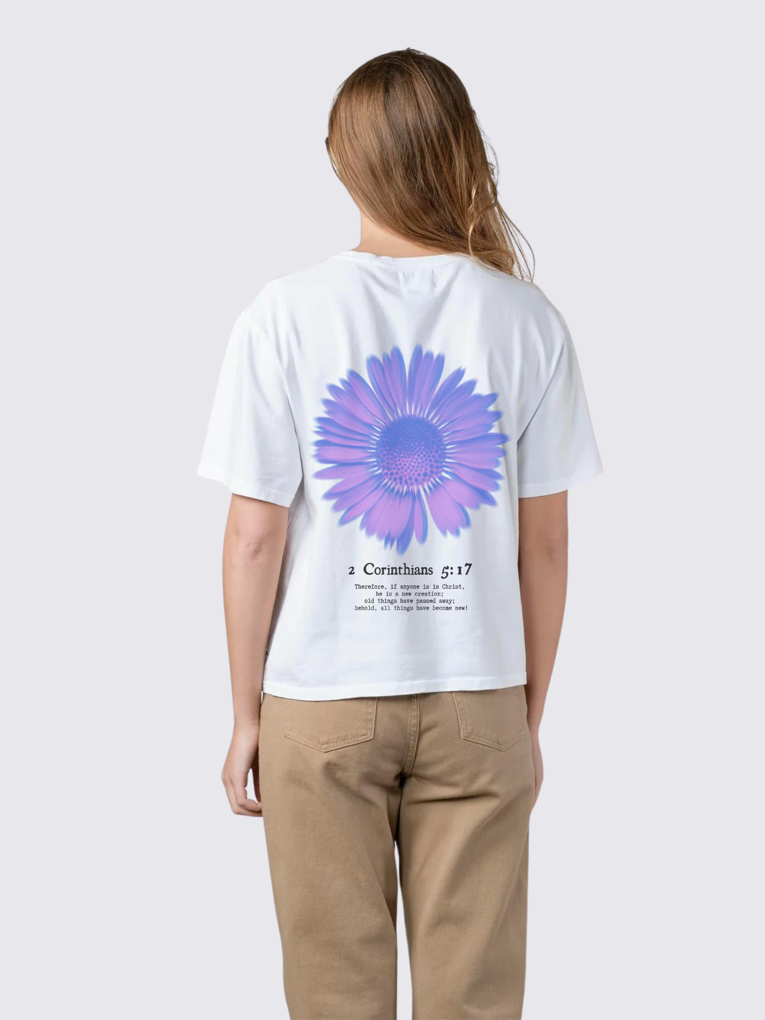 Woman wearing the SĒK Apparel Made New Flower Tee in white — back view with floral design and 2 Corinthians 5:17 scripture, faith-inspired Christian graphic tee