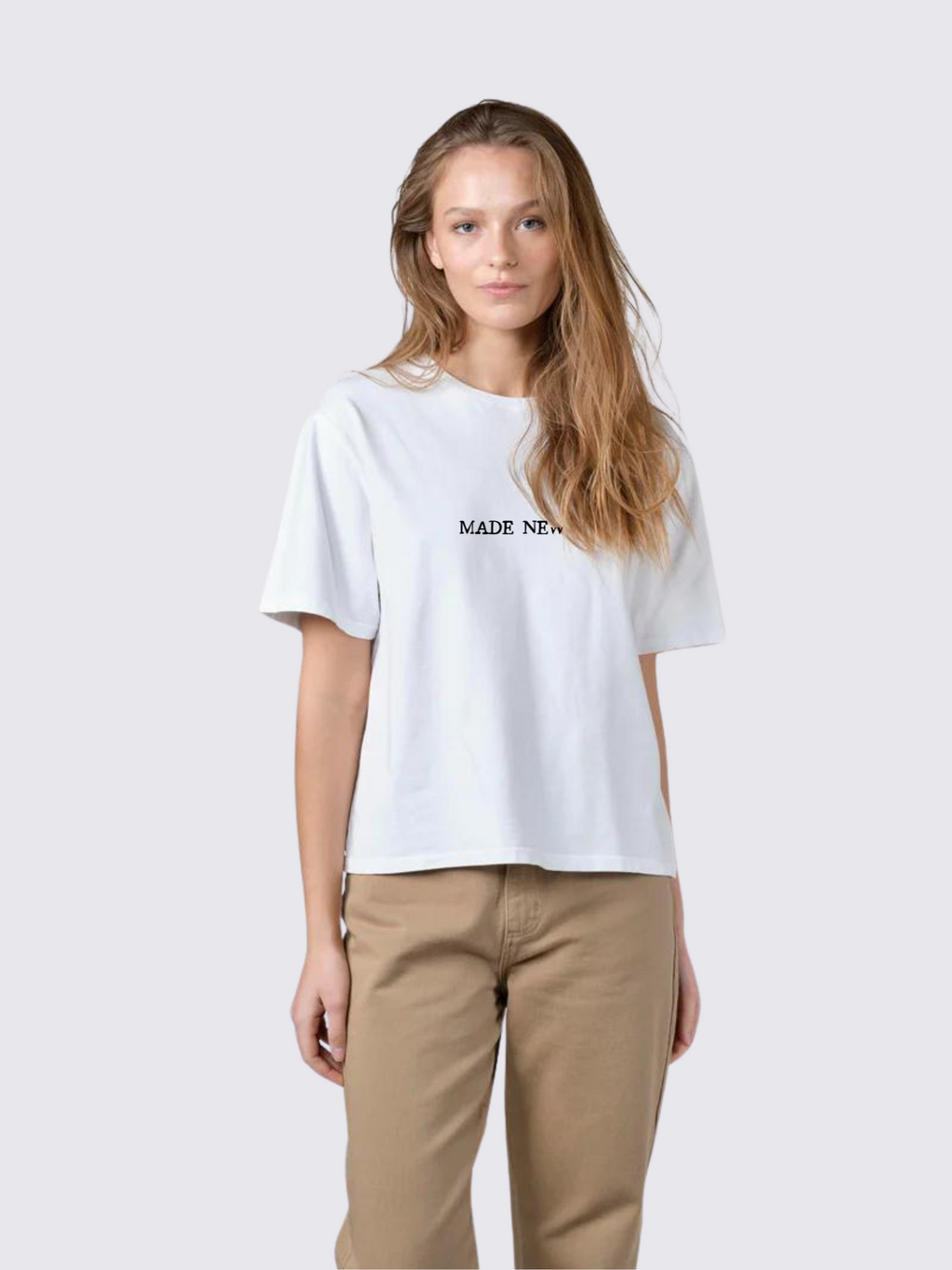 Woman wearing the SĒK Apparel Made New Flower Tee in white — front view of faith-inspired Christian graphic tee with floral design, referencing 2 Corinthians 5:17