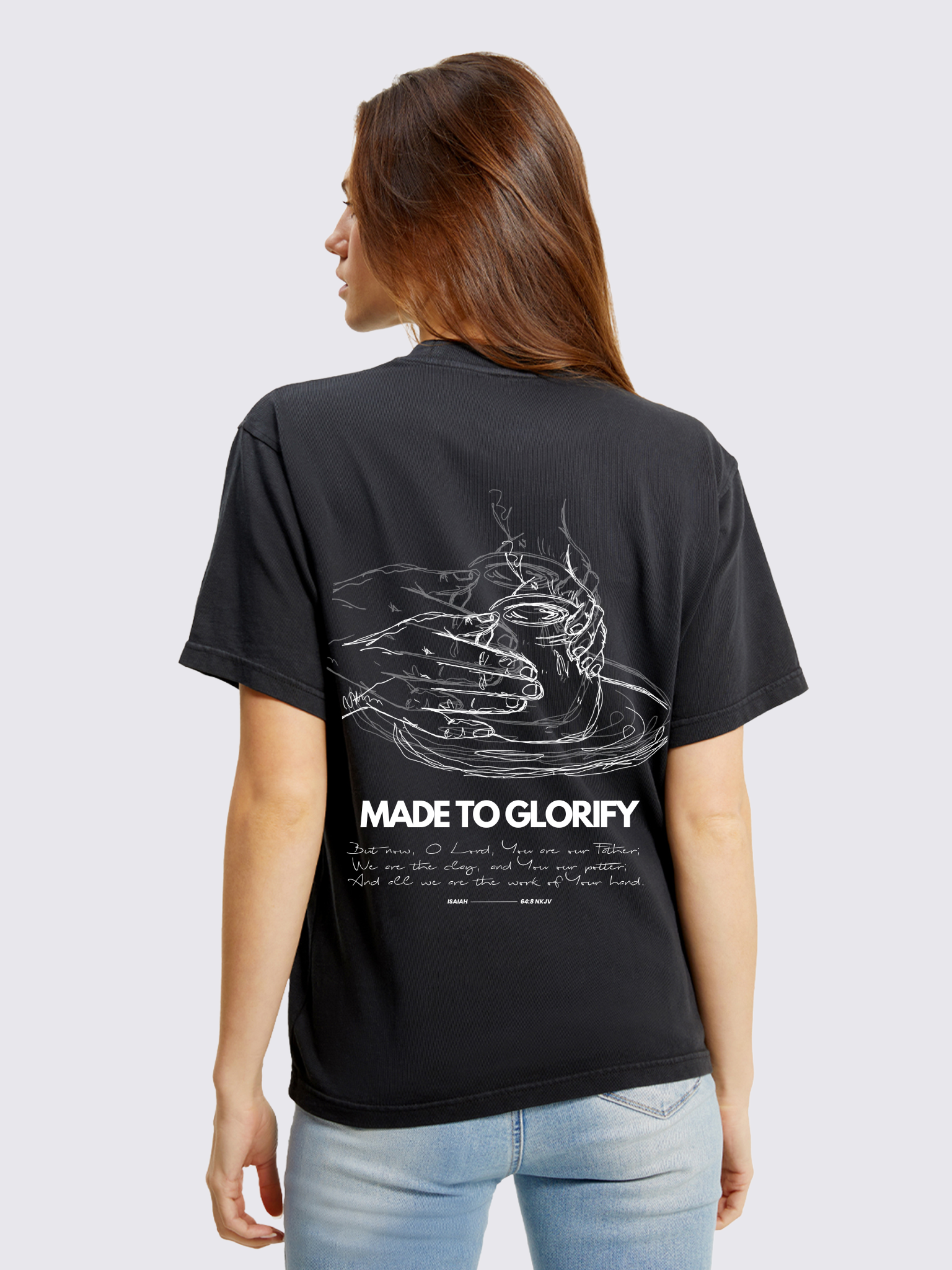 Woman wearing the SĒK Apparel Made to Glorify Tee in faded black — back view with bold 'Made to Glorify' text, faith-inspired Christian graphic tee