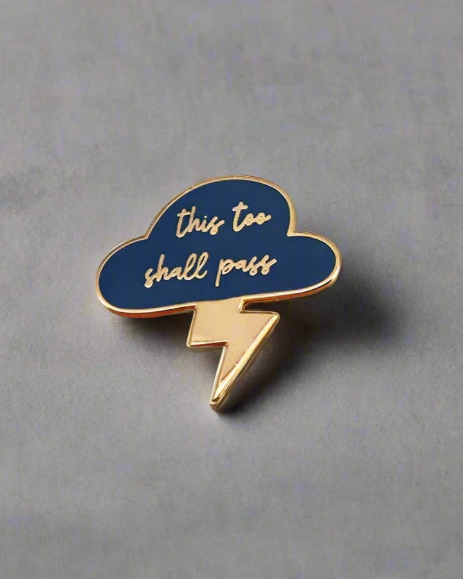 SĒK Apparel This Too Shall Pass enamel pin — blue cloud and lightning bolt design with 'This Too Shall Pass' text, faith-inspired Christian encouragement lapel pin