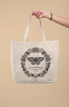 SĒK Apparel Transformed Butterfly Tote — product shot of faith-inspired Christian canvas tote bag with butterfly design and 'Transformed' text, referencing Romans 12:2