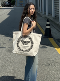 Woman carrying the SĒK Apparel Transformed Butterfly Tote on a street — faith-inspired Christian tote bag with butterfly graphic and 'Transformed' text, referencing Romans 12:2