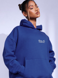 Woman wearing the SĒK Apparel Unfailing Love Hoodie in navy — front view of faith-inspired Christian pullover hoodie with embroidered 'Unfailing Love' text, referencing 1 John 4:10